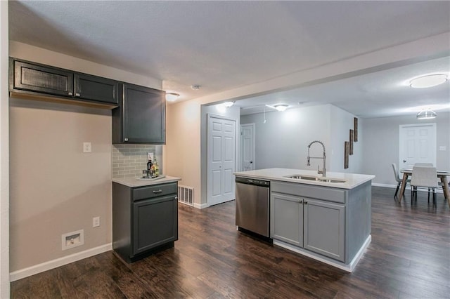 kitchen with dark hardwood / wood-style flooring, sink, stainless steel dishwasher, and a center island with sink