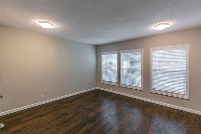 unfurnished room featuring a textured ceiling, a wealth of natural light, and dark hardwood / wood-style floors