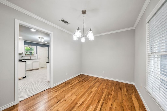 spare room featuring a chandelier, light hardwood / wood-style floors, and ornamental molding