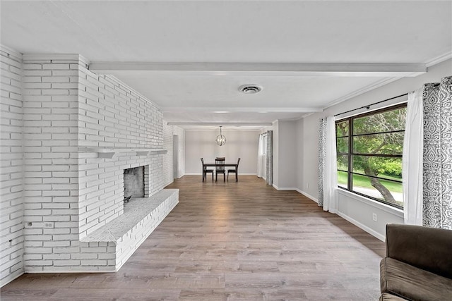 living room with hardwood / wood-style flooring, beamed ceiling, and a brick fireplace