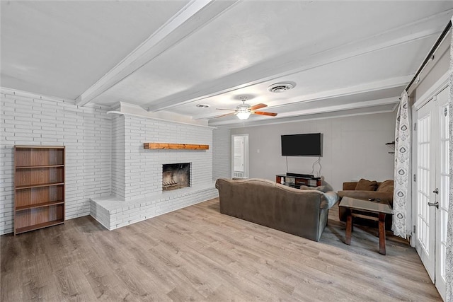 living room with beam ceiling, a wealth of natural light, light hardwood / wood-style flooring, and a brick fireplace