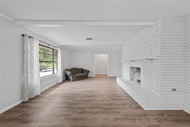 living area with crown molding, wood-type flooring, and a brick fireplace