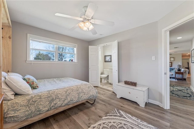 bedroom featuring ensuite bath, light wood-type flooring, baseboards, and a ceiling fan