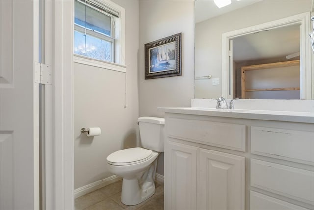 half bath featuring baseboards, toilet, vanity, and tile patterned flooring