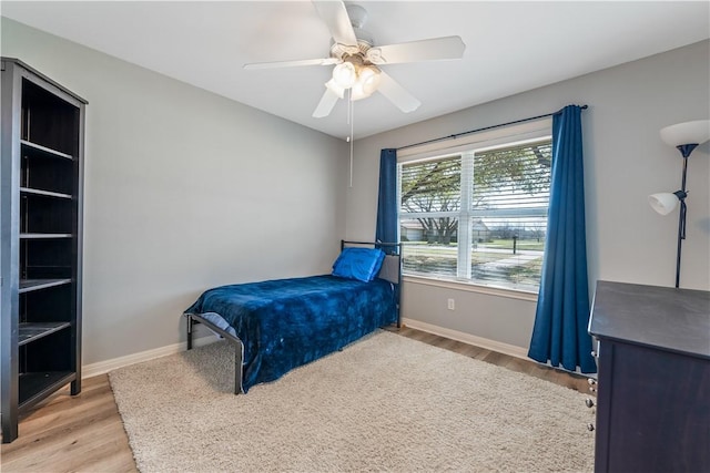 bedroom with a ceiling fan, light wood-type flooring, and baseboards