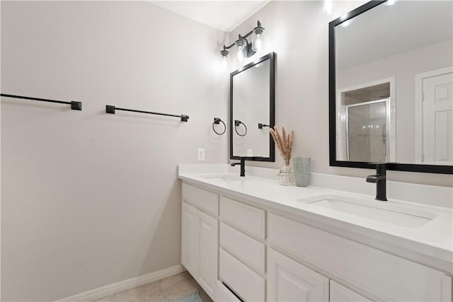 bathroom featuring a shower stall, double vanity, baseboards, and a sink