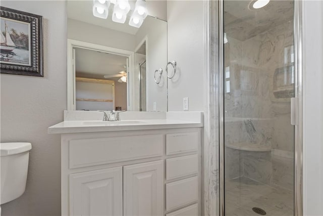 full bathroom featuring a marble finish shower, toilet, ceiling fan, and vanity