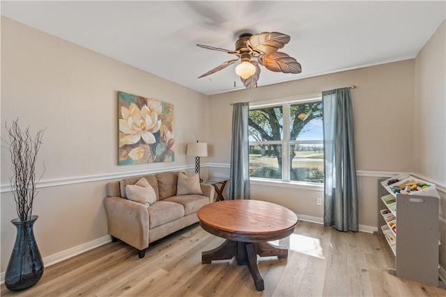 living area with ceiling fan, baseboards, and light wood-style floors