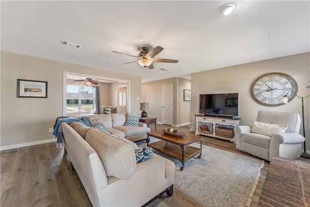 living area featuring a ceiling fan, wood finished floors, visible vents, and baseboards