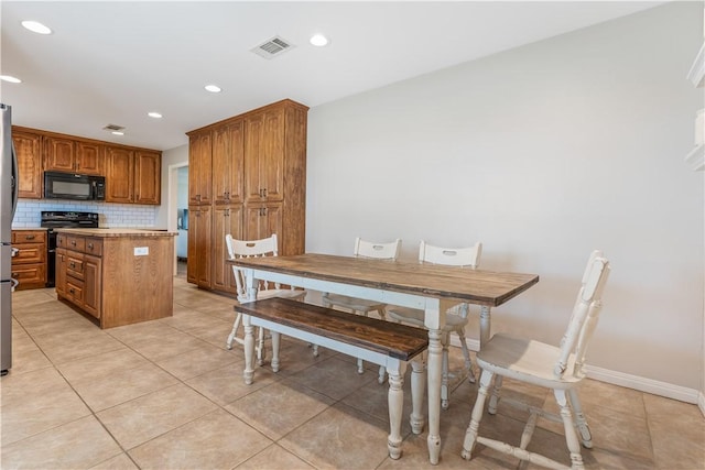 kitchen with visible vents, brown cabinets, range with two ovens, black microwave, and tasteful backsplash