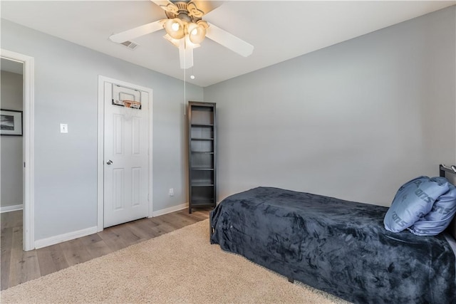 bedroom featuring visible vents, ceiling fan, baseboards, and wood finished floors