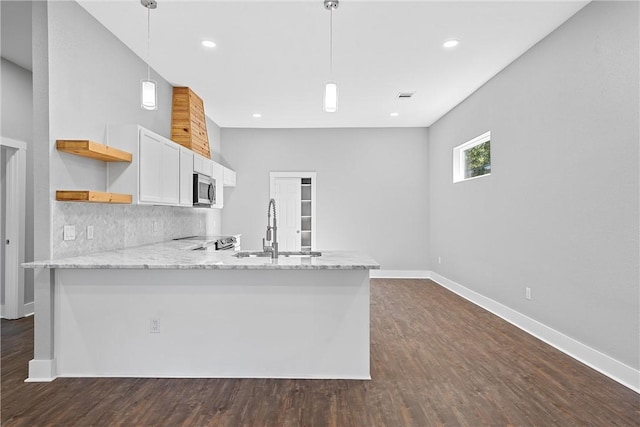 kitchen with kitchen peninsula, pendant lighting, appliances with stainless steel finishes, sink, and white cabinets