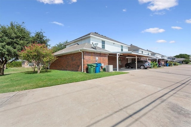 exterior space with central air condition unit, a yard, and a carport