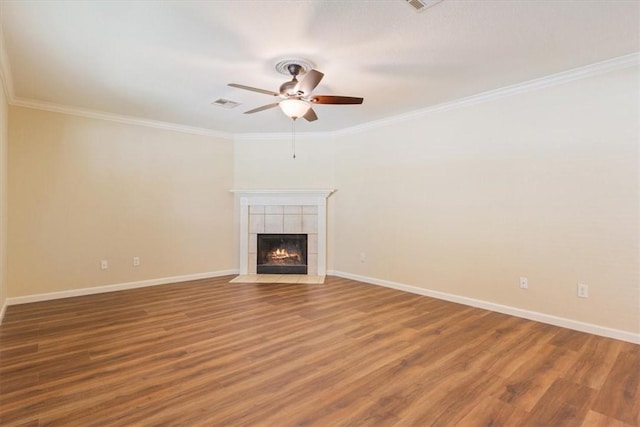 unfurnished living room with a tiled fireplace, ceiling fan, wood-type flooring, and ornamental molding