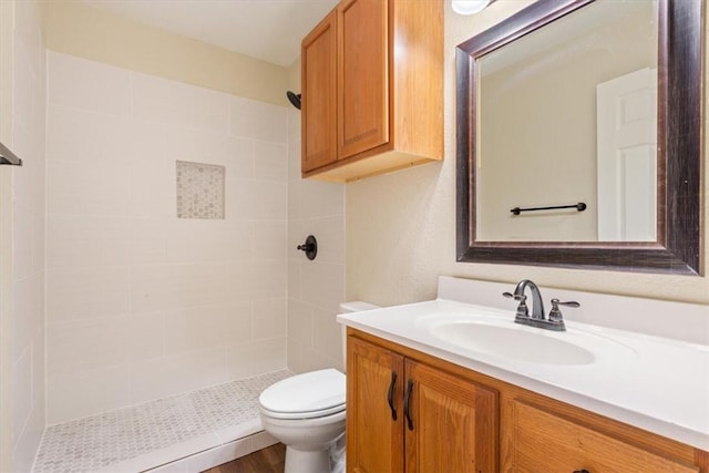 bathroom featuring tiled shower, hardwood / wood-style floors, vanity, and toilet