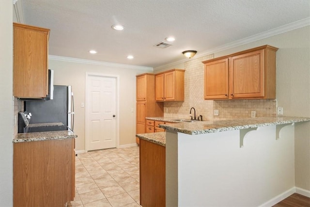 kitchen with a kitchen bar, light stone counters, kitchen peninsula, and sink