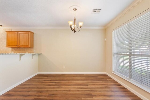 unfurnished dining area featuring ornamental molding, dark hardwood / wood-style floors, and a notable chandelier