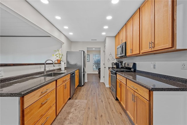 kitchen featuring dark stone counters, sink, light wood-type flooring, and appliances with stainless steel finishes