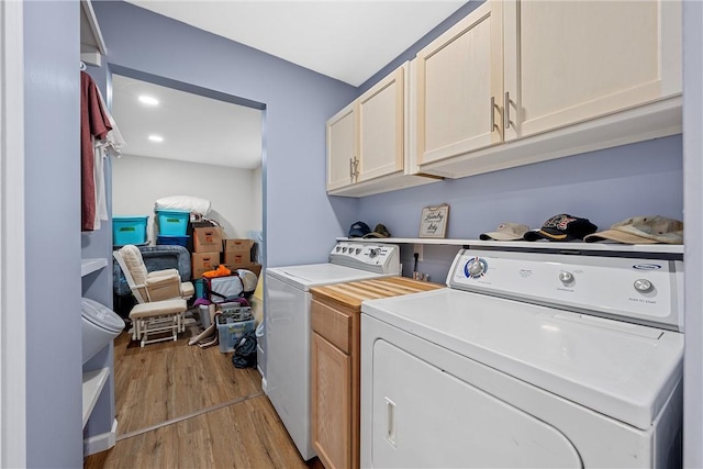 laundry area featuring separate washer and dryer, cabinets, and light wood-type flooring