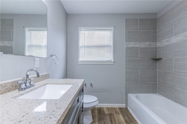 full bathroom with vanity, tiled shower / bath, wood-type flooring, and toilet