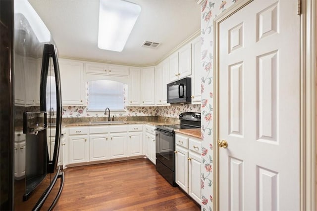 kitchen with white cabinetry, wood-type flooring, sink, and black appliances