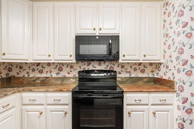 kitchen featuring dark stone countertops, white cabinets, and black appliances