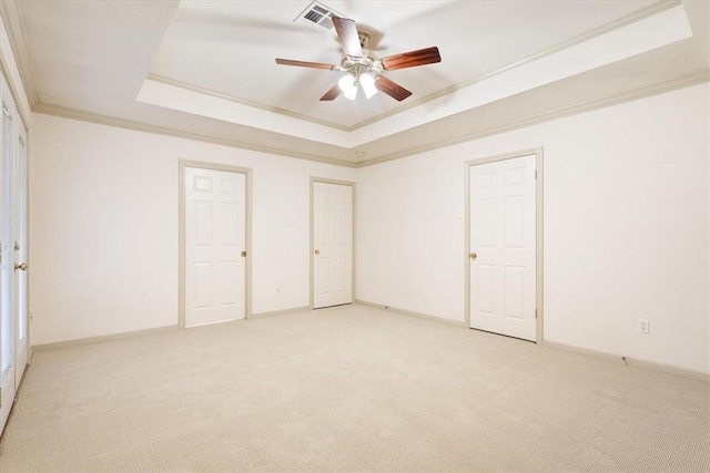 unfurnished bedroom featuring crown molding, ceiling fan, a tray ceiling, and carpet