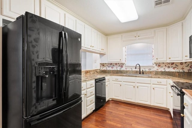 kitchen with white cabinetry, hardwood / wood-style flooring, sink, and black appliances