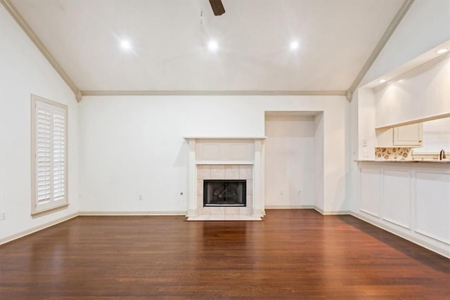 unfurnished living room with lofted ceiling, dark hardwood / wood-style flooring, a tiled fireplace, ornamental molding, and ceiling fan