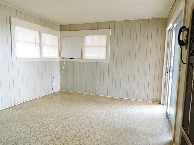 carpeted spare room featuring wood walls