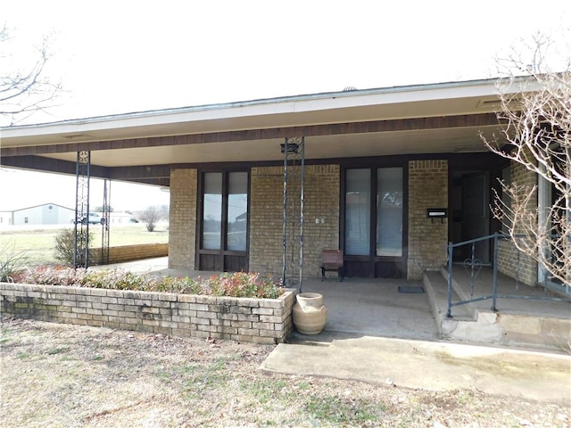 entrance to property featuring covered porch and brick siding