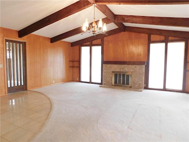 unfurnished living room featuring vaulted ceiling with beams, light tile patterned floors, a brick fireplace, wooden walls, and a chandelier