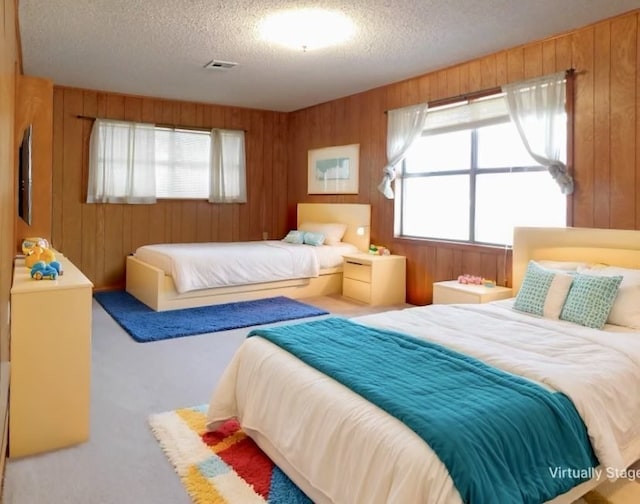 bedroom featuring a textured ceiling, carpet floors, visible vents, and wooden walls