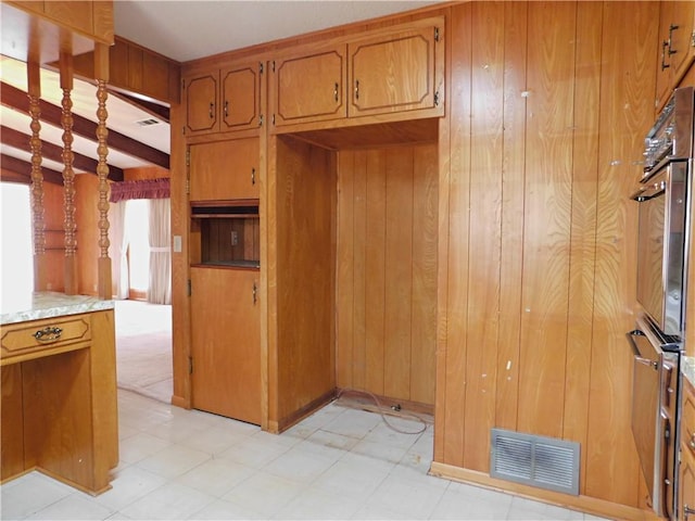 kitchen featuring wood walls, visible vents, and brown cabinetry