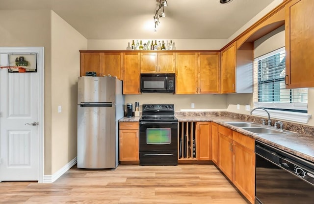 kitchen featuring sink, track lighting, black appliances, and light hardwood / wood-style floors