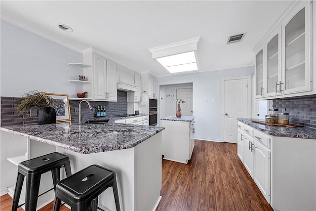 kitchen featuring white cabinets, dark hardwood / wood-style floors, backsplash, and sink