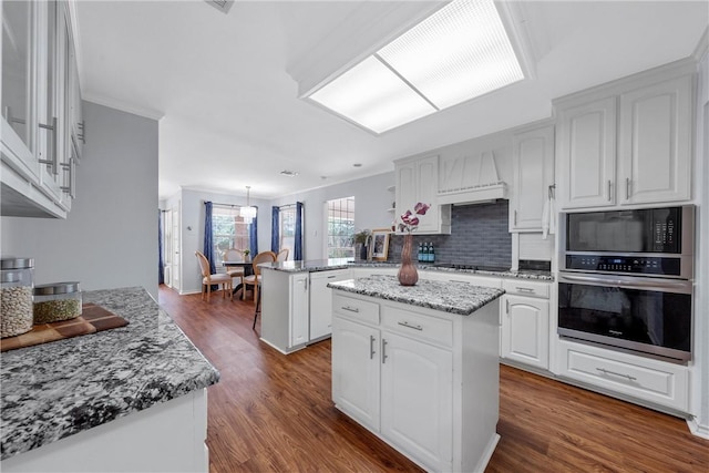 kitchen with kitchen peninsula, wood-type flooring, white cabinetry, and a kitchen island