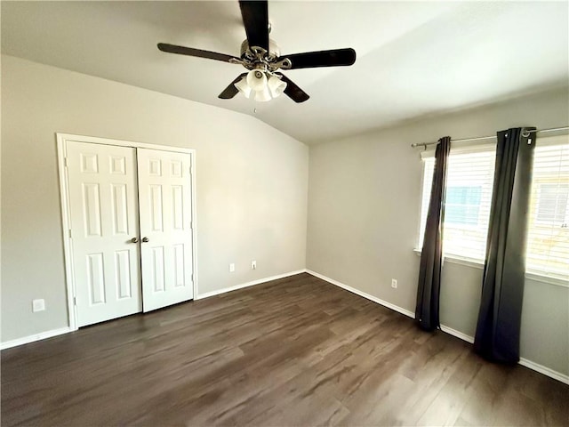 unfurnished bedroom with lofted ceiling, dark hardwood / wood-style floors, ceiling fan, and a closet