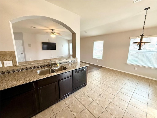 kitchen with sink, ceiling fan, black dishwasher, light stone countertops, and decorative light fixtures