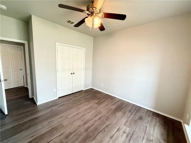 unfurnished bedroom with dark wood-type flooring, a closet, and ceiling fan