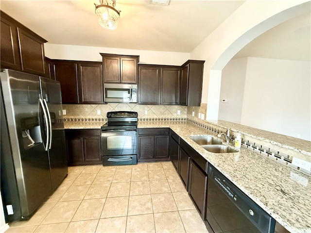 kitchen featuring light stone counters, sink, backsplash, and black appliances