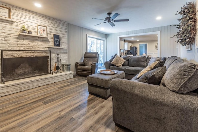 living room with ceiling fan, wood-type flooring, and a fireplace