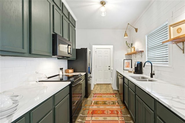 kitchen with stainless steel appliances, green cabinetry, crown molding, and sink