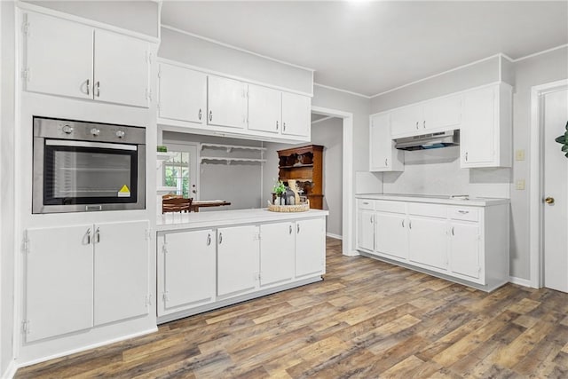 kitchen with white cabinets, wood-type flooring, oven, and ornamental molding