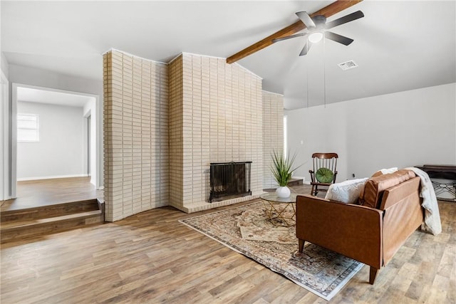 living room featuring a brick fireplace, ceiling fan, lofted ceiling with beams, and light hardwood / wood-style floors