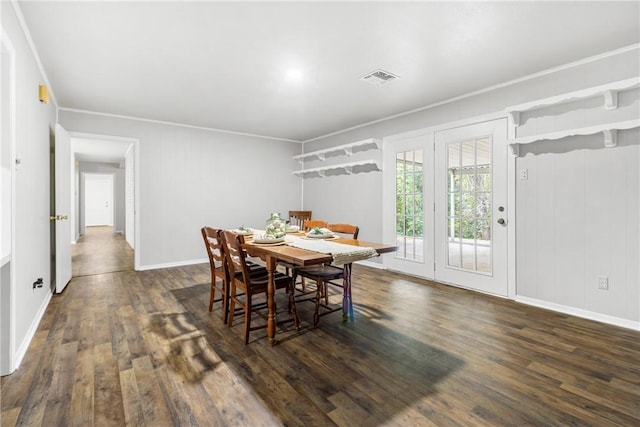 dining room featuring wood walls, dark hardwood / wood-style flooring, and crown molding