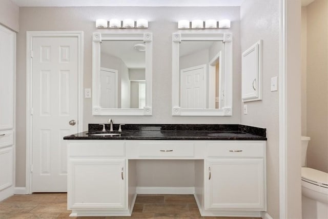 full bath featuring double vanity, wood finished floors, a sink, and toilet