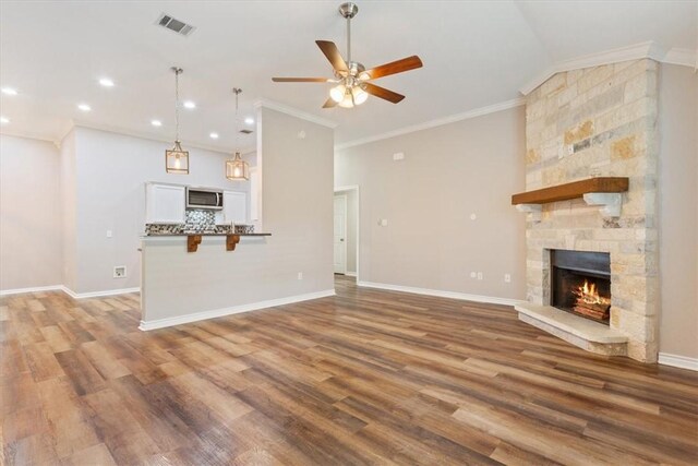 unfurnished living room featuring visible vents, a fireplace, ornamental molding, and wood finished floors