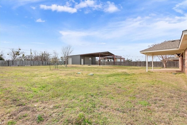 view of yard with fence, a pole building, and an outbuilding