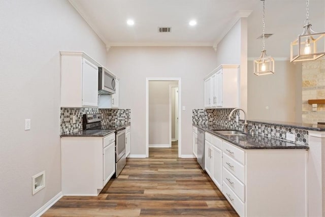 kitchen featuring wood finished floors, a sink, visible vents, ornamental molding, and appliances with stainless steel finishes